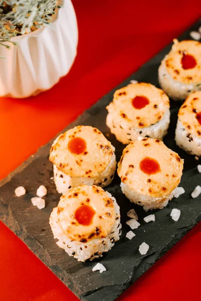 Siyah bir tabakta servis edilen baharatlı sosla kaplı eşsiz suşi tabakları.