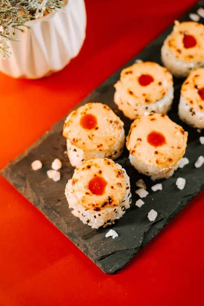 Lezzetli suşi ruloları. Siyah bir tabakta parlak bir tepsi.
