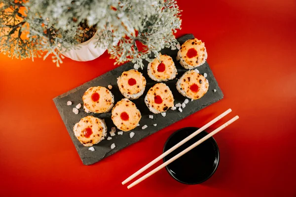 Siyah taş tabakta servis edilen renkli malzemelerle kaplı suşi ruloları.