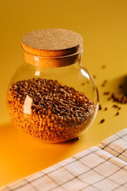 Karabuğday, güneşli bir günde sarı bir arka planda cam bir kavanozda saklanır.