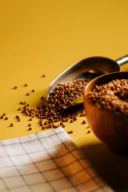 Bir kasede karabuğday homurdanması ve parlak sarı bir arka planda kepçe.