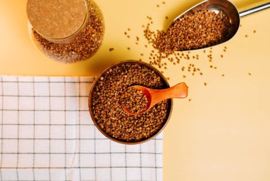 Karabuğday ahşap bir kasede ve bir kaşıkla sarı bir tezgahta inliyor.