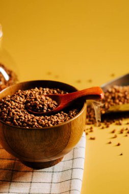 Karabuğday, yumuşak bir yüzeyde, parlak sarı bir zemin ile ahşap bir kasede inliyor.