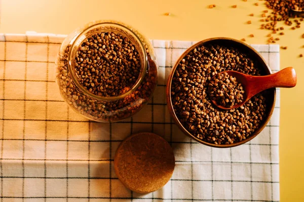 Karabuğday tarlaları cam kavanozda ve kareli kumaş üzerinde ahşap kasede sergilenir.