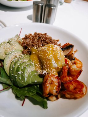 Parlak bir yemek masasında nefis karides ve kinoalı avokado salatası.