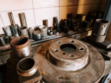 Metal atölyesi, sıcak ışıklandırmalı kırsal bir ortamda çeşitli araç ve parçaları sergiliyor