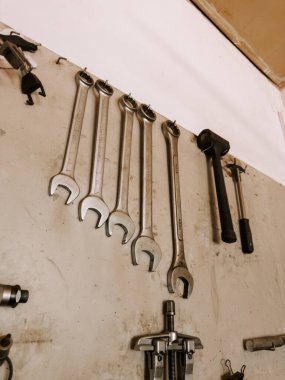 Bir atölyenin duvarında düzenlenmiş aletler kullanıma hazır anahtarlar ve çekiç gösteriyor.