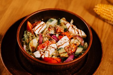 Tahta bir masada, kırsal bir kasede servis edilen lezzetli taze salata.