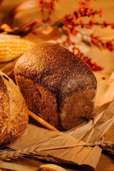 Köy ahşap masada mevsimlik dekorla sergilenen taze zanaatkar ekmeği.