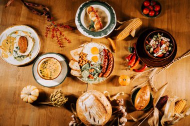 Mevsimlik hasat ziyafeti ahşap bir masada çeşitli yemekler ve taze malzemelerle.