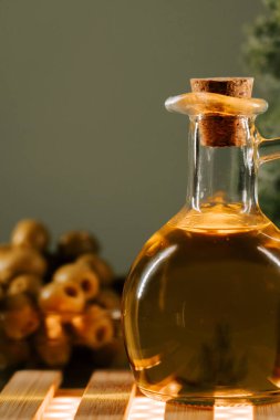 Cam bir şişede, ahşap bir yüzeye tıpa takılmış zeytin yağı.
