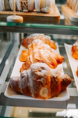 Modern bir fırında cam raflarla sergilenen taze kruvasanlar.