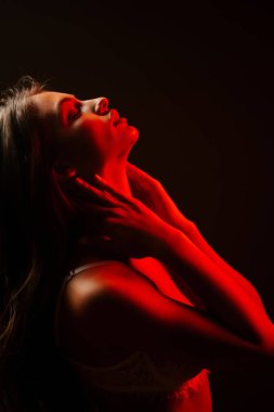 Kadın iç çamaşırlarıyla zarif bir şekilde poz veriyor Bir akşam saatinde kırmızı neon ışıkların altında