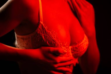 Seksi kadın gece parıldayan kırmızı neon ışıkların altında iç çamaşırlarıyla poz veriyor.