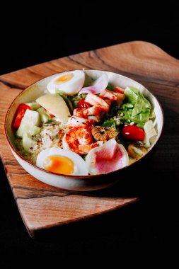 Tahtada karides, yumurta ve renkli sebzelerle taze salata.