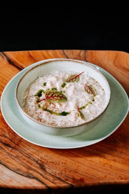 Ahşap tepside servis edilen lezzetli kremalı sütlaç, otlar ve süslemelerle.