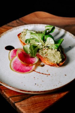 Taze yeşillik ve ahşap bir tahtada servis edilen turplu lezzetli avokado tostu.