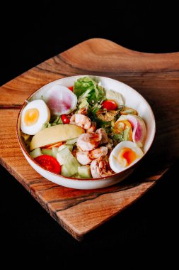Tahtada taze karides salatası, karışık yeşillikler, kiraz domatesleri ve kaynamış yumurta.
