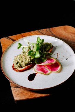 Bir gurme lokantasında turp dilimli kızarmış ekmeğe sürülmüş lezzetli avokado.