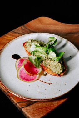 Tahta bir tabakta garnitürle servis edilen lezzetli avokado tostu.