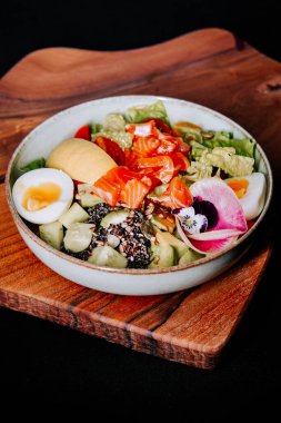 Renkli deniz ürünleri salatası ve taze sebzeler sıradan bir yemek ortamında ahşap tahtada servis ediliyor.