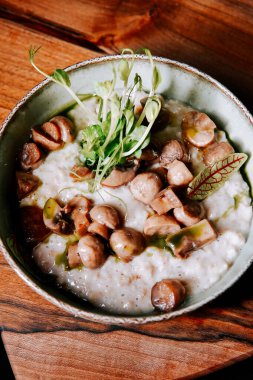 Köy ortamında servis edilen mantarlı ve yeşillikli lezzetli bir kase kremalı risotto.