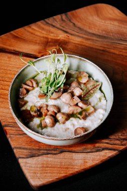 Ahşap bir tahtanın üzerinde kırsal bir kasede servis edilen lezzetli mantar yemeği.