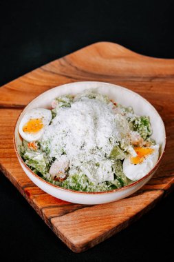 Ahşap tabakta servis edilen haşlanmış yumurta ve peynirli taze salata.