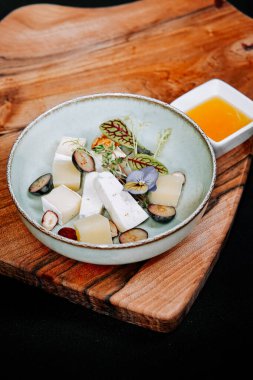 Tahta üzerinde peynir, meyve ve yenilebilir çiçeklerle yaratıcı gıda sunumu