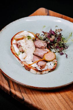 Köy tabaklarında servis edilen et ve soslu eşsiz bir açık yüzlü sandviç.