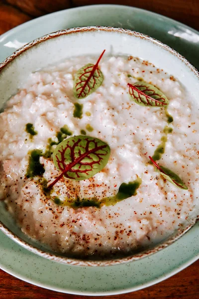 Taze otlarla dolu kremalı risotto kasesi ve sade bir ortamda baharat.
