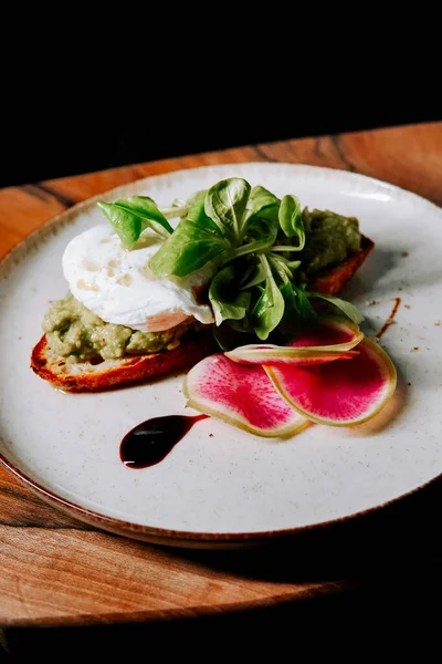 Minimalist tabakta servis edilen kremalı ve taze yeşillikli gurme tostu