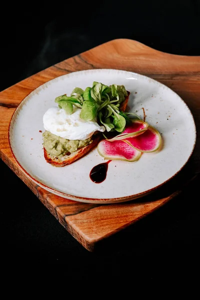 Tahtada haşlanmış yumurta, yeşillik ve turpla servis edilen leziz açık yüzlü sandviç.