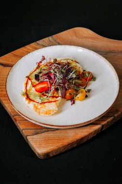 Ahşap bir tahtanın üzerinde servis edilen renkli malzemelerle servis edilmiş lezzetli bir tabak yumuşak omlet.