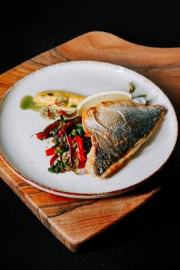 Ahşap tahtada servis edilen rengarenk sebzeli ızgara balık.
