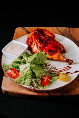 Keskin soslu ızgara tavuk taze salata ve ahşap tabakta sosla servis edilir.