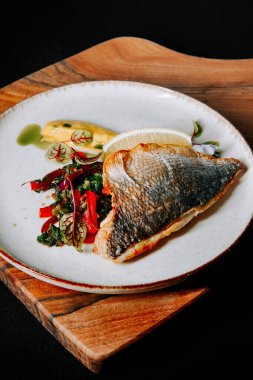 Lezzetli bir sunumda taze sebze ve limonla servis edilen leziz ızgara balık.