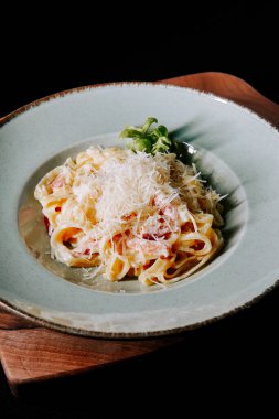 Köy tahtasında taze otlarla servis edilen lezzetli kremalı fettucine makarna.