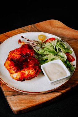 Lezzetli ızgara tavuk taze salata ve ahşap tahtada kremalı sos ile servis edilir.