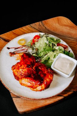 Restoran ortamında ahşap tahtada servis edilen taze salatalı ızgara tavuk.