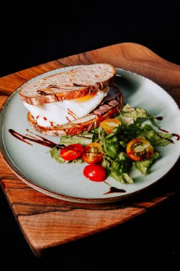 Tahtada servis edilen et ve taze sebzeli lezzetli sandviç.