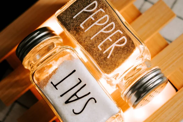 Gündüz vakti mutfak ortamında ahşap bir yüzeyde tuzluk ve biber karıştırıcılar.