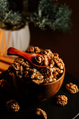 Tahta bir kasede soyulan cevizler ve yumuşak ışıkta sergilenen bir kaşık.