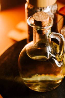 Cam bir şişedeki ayçiçeği yağı, doğal ışık ve arkaplan parçalarıyla ahşap bir masada sergilenir.