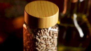 Cam kavanozda ay çekirdeği ve akşam ışığında evdeki masada ahşap kapak.