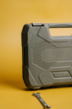 Alet çantası sarı arka planda duruyor ve tamir işleri için anahtarı yanında.