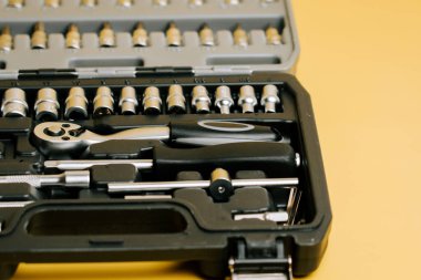 Çeşitli boyutlarda soketler ve sarı bir yüzey üzerinde cırcır olan araç kiti düzeneği gösterir