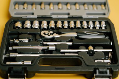 Tool set with various sockets and ratchet on yellow background