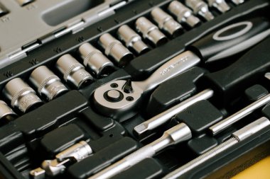 Tool set with various sockets and a ratchet located on a workbench for repairs