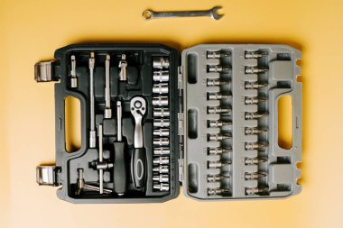 Çeşitli soketlere sahip araç seti ve sarı arka planda bir çalışma düzeneği gösteren bir cırcır.